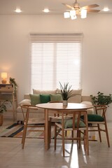 Stylish dining table with chairs and comfortable sofa in room. Interior design
