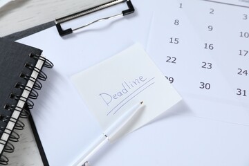 Sticky note with word Deadline, clipboard, calendar, pen and notebook on table, closeup