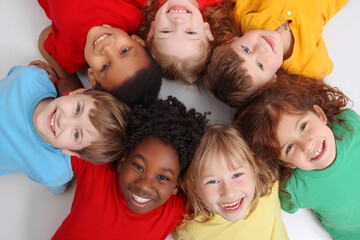 Diverse kids smile lying in circle. Teamwork, unity, friendship concept. Use for marketing, education, website.