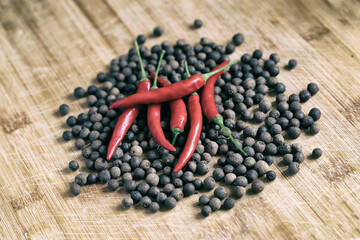 bright hot red chili peppers on a wooden surface surrounded by aromatic peppercorns