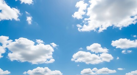 Fototapeta premium Bright blue sky with fluffy white cumulus clouds scattered across the frame, illuminated by sunlight.