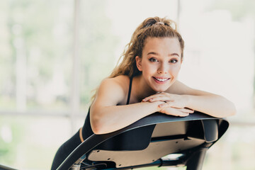 Athletic Energetic Woman Exercising Indoors on Treadmill in Modern Fitness Setting, Smiling with...