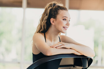 Active young woman with blonde hair relaxing on treadmill indoors after workout at the gym smiling...