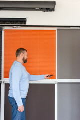 Business owner demonstrating smart control of roller blinds in a modern showroom of various types of sunshades. Motorized blinds integrate convenience with stylish interior shading solutions.