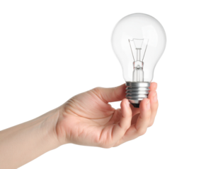 A hand is holding a clear incandescent light bulb by its metal base.