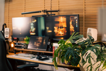 A warm and cozy desk setup featuring triple monitors, notebook, microphone, and green plants, styled in a minimalist Japanese aesthetic for creative work.