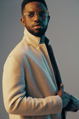 Stylish black man in modern attire with glasses posing confidently against a colorful backdrop,...