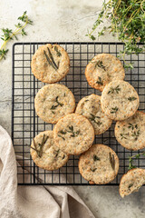 Shortbread cheese cookies with aromatic herbs on cooling rack on rustic textured background. Savory parmesan cookies top view