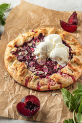 French Galette or pie with plums and almonds served with ice cream scoops on parchment paper...
