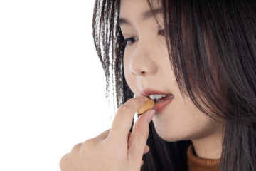 Young Asian woman taking a pill, representing wellness and self-care. Daily routine of taking a vitamin, supplement, or medicine for health. isolated on white background with clipping path.