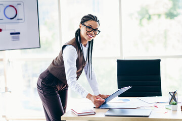 Confident businesswoman analyzing data in an office setting, showcasing professional expertise and...