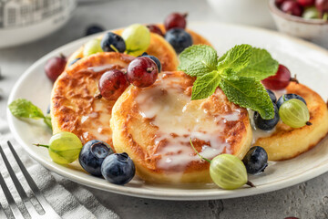 Cottage cheese pancakes with berries and condensed milk close up. Homemade dessert syrniki for healthy breakfast