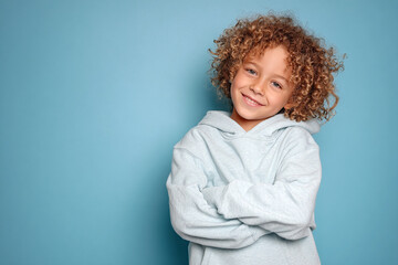 Smiling child poses with confidence. Cute curly haired kid for advertising, marketing, design, or social media.