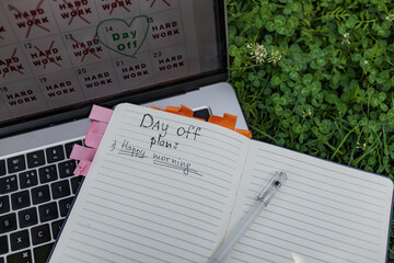 Detailed image of paper planner with 'Happy morning' plan, placed on open laptop in grass. Pink and...