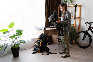 Female Backpacker packing backpack rucksack for her trip in the living room at home