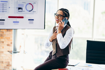 Businesswoman Talking on Smartphone in Modern Office Environment Surrounded by Professional Tools...