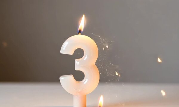 Number three candle burning with sparks for a third birthday