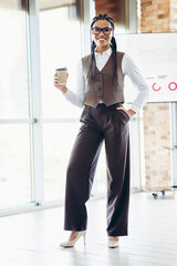 Professional businesswoman in formal attire with natural confidence and modern style standing in an...