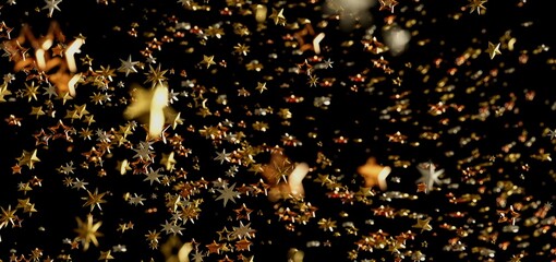 Sparkling gold and bronze stars falling on black background. Perfect for holidays, celebrations,...