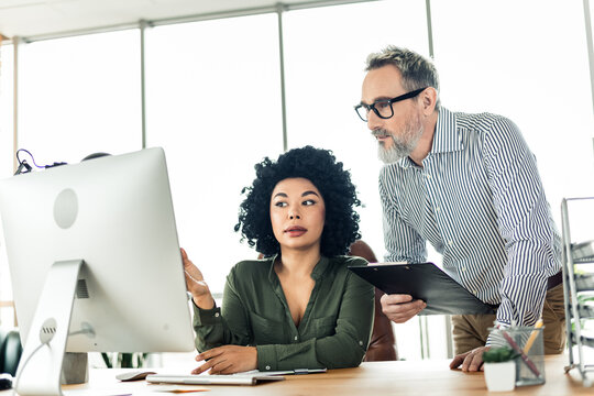 Professional collaboration in modern office setting showcasing teamwork and mentoring between colleagues during work discussion