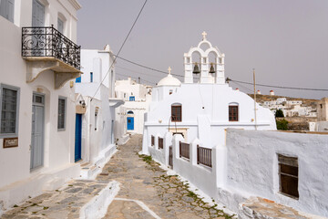Fototapeta premium The street with a typical architecture of Greek style whitewashed houses and a white church in Chora village, Amorgos island, Cyclades, Greece