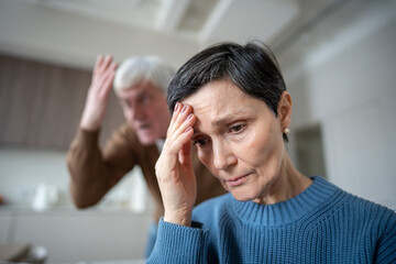 Upset withdrawn wife shielding herself in fear, trying to ignore husband hysterical outbursts....