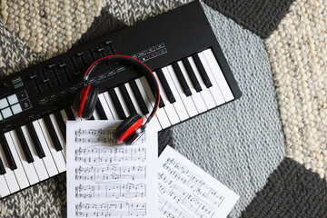 MIDI keyboard, music sheets and headphones on carpet, flat lay