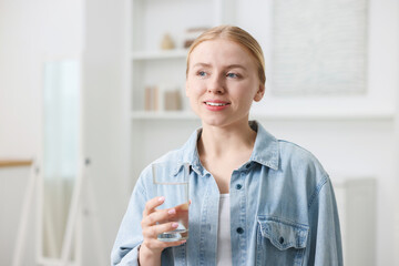 Young woman with glass of water at home