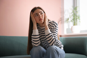 Woman suffering from paranoia on sofa at home