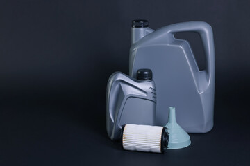 Motor oil in plastic canisters, filter and funnel on dark grey background, space for text