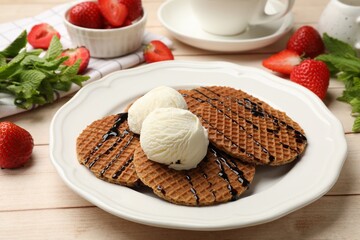 Tasty Dutch waffles (stroopwafels) with ice cream and chocolate sauce on light wooden table, closeup