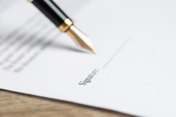 Signing notary document with fountain pen at table, selective focus
