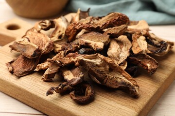 Pieces of dried mushrooms on light wooden table, closeup
