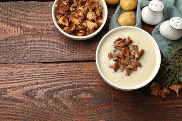 Tasty cream soup, thyme and dry chanterelle mushrooms on wooden table, flat lay. Space for text