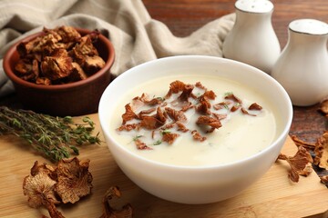 Tasty cream soup with mushrooms and thyme in bowl on wooden table, closeup