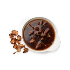 Tasty soup in bowl and dry chanterelle mushrooms isolated on white, top view