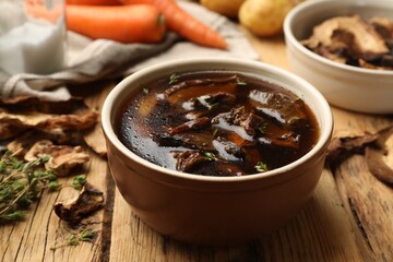 Tasty soup with mushrooms and thyme in bowl on wooden table, closeup