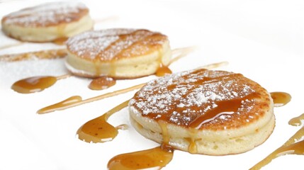 Fluffy pancakes drizzled with golden caramel sauce and dusted with powdered sugar