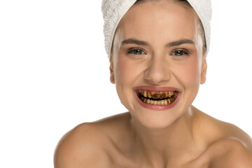 Close-up of young woman with chocolate-stained teeth smiling after bite, studio shot on white...