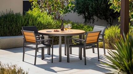 Round outdoor patio table and four chairs set on a stone patio with wine and fruit.