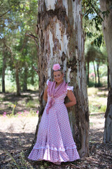 A beautiful young Spanish woman dressed in a traditional pink and white flamenco dress with a...