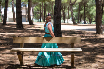 A beautiful young Spanish woman dressed in a traditional green flamenco dress with a flower in her...