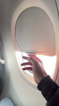 A passenger's point of view opening the airplane window.