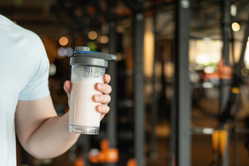 Close up of mans hand with protein shaker at gym. Fitness healthy lifestyle concept. Supplement...