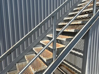 Staircase with rust stains against grey wall on exterior wall of city building