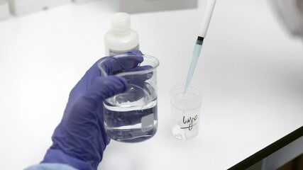 scientist using pipette to transfer liquid from glass beaker into plastic container during laboratory experiment in sterile environment with gloves and lab tools - Powered by Adobe