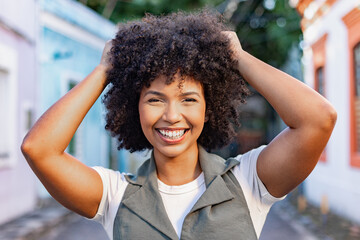 Afro-Brazilian woman smiling and playing with her natural curls on a colorful colonial...