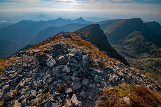Aerial view of rocky ridges with sparse vegetation leading to distant, hazy peaks under a bright sky, JamnÃk, Žilina Region, Slovakia.