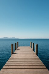  Symmetrical wooden pier stretching into a calm lake under a clear blue sky, with mountains in the distance.