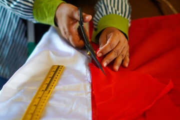 The process of cutting cloth to sew the red and white flag, Indonesia's national flag. The theme is...